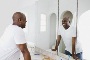 Los Angeles, California, USA --- Man looking in bathroom mirror, smiling --- Image by © Blue Images/Corbis